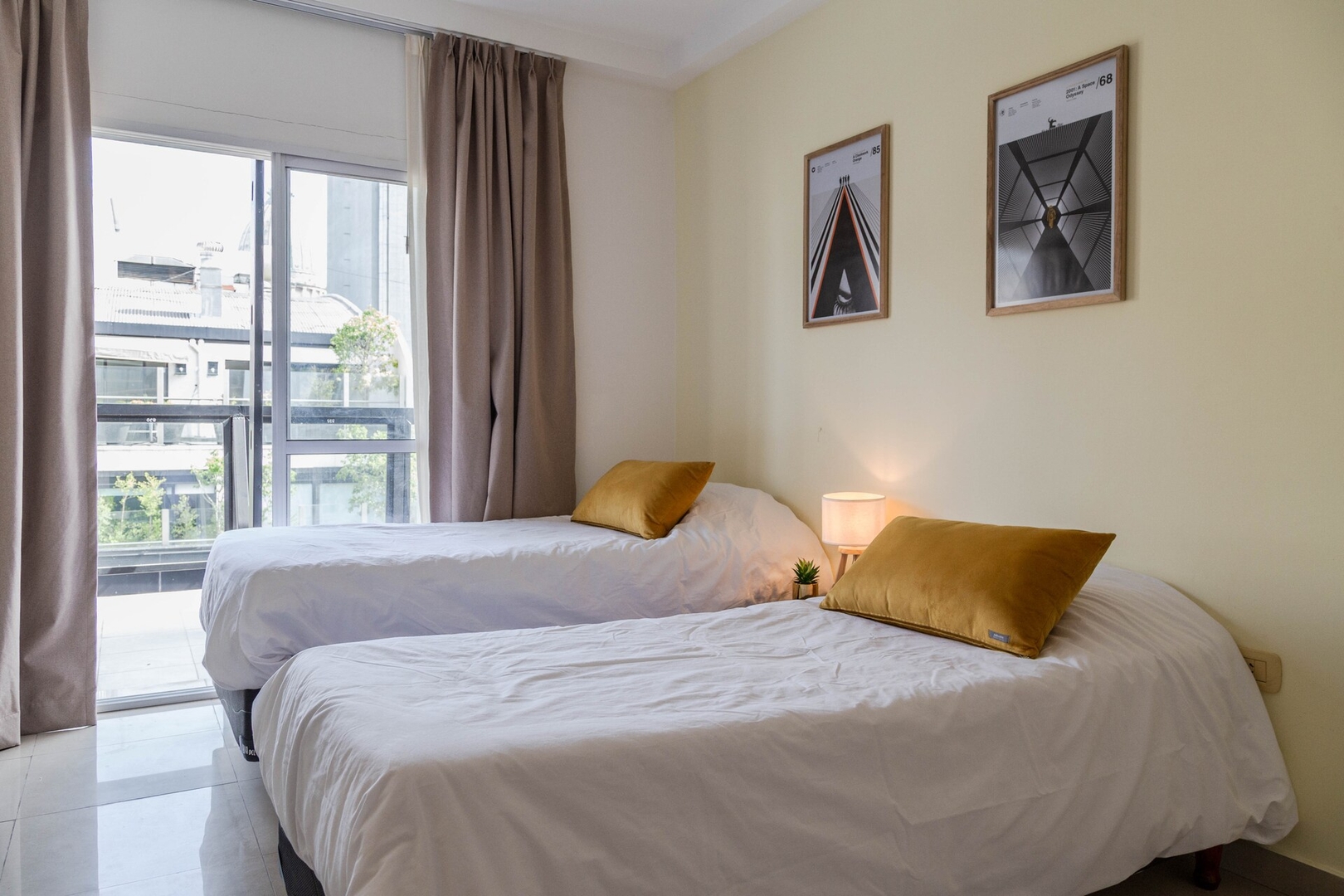 Two separate beds beside a balcony door in a Buenos Aires apartment