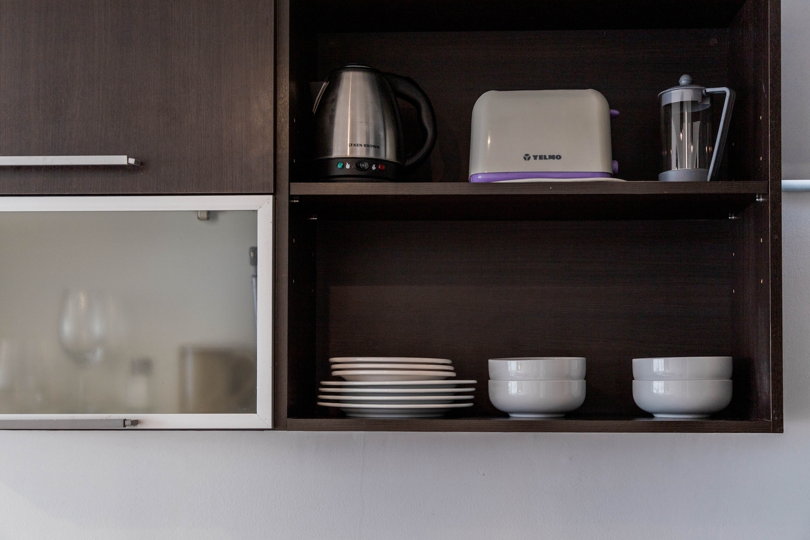 Kettle, toaster, coffee maker and dishes on kitchen shelves in a Buenos Aires studio