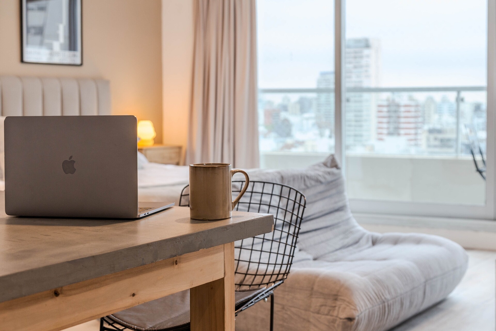 Laptop and mug on a table beside the living area in a Buenos Aires studio