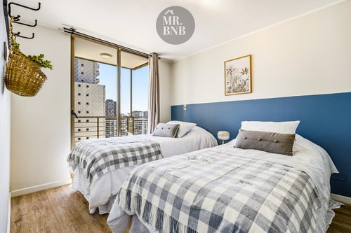 Dormitorio con dos camas, cabecera azul y canasto colgante en la pared