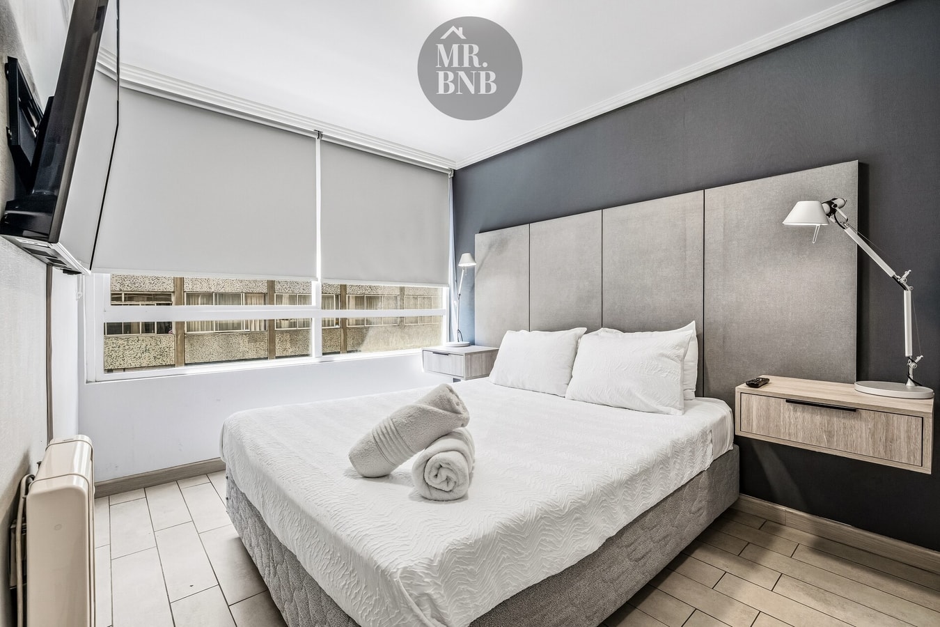 Dormitorio con cama, cabecero tapizado y ventana con cortina