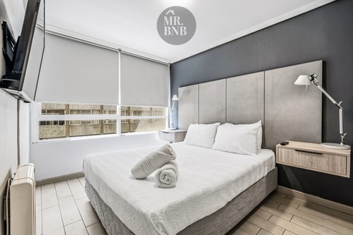 Dormitorio con cama, cabecero tapizado y ventana con cortina