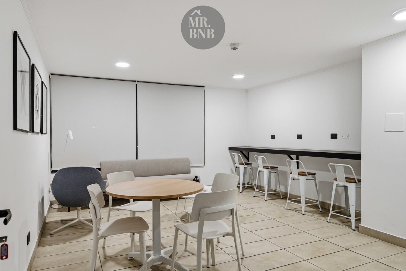 Sala cowork del edificio con mesa redonda, sillas y barra alta con banquetas