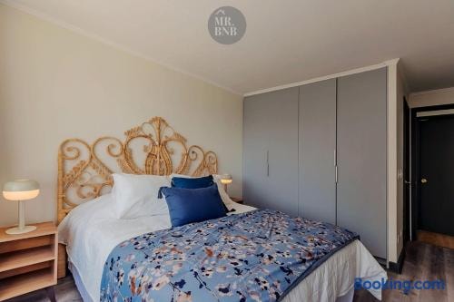 Dormitorio con cama, veladores con lámparas y cabecero de mimbre.