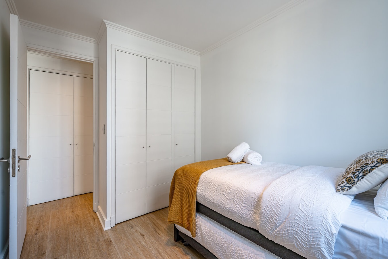 Dormitorio con cama, puertas de clóset blancas y cubrecama mostaza