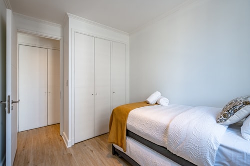 Dormitorio con cama, puertas de clóset blancas y cubrecama mostaza