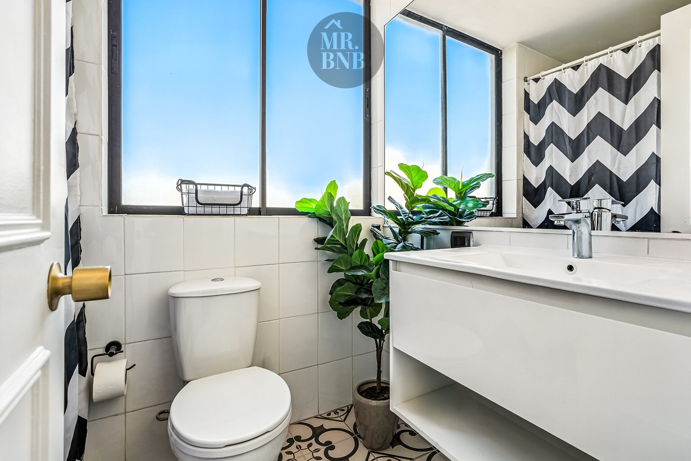 Baño con lavamanos, ducha con cortina a rayas y planta decorativa