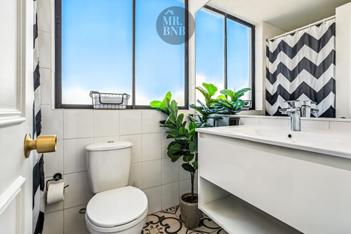 Baño con lavamanos, ducha con cortina a rayas y planta decorativa