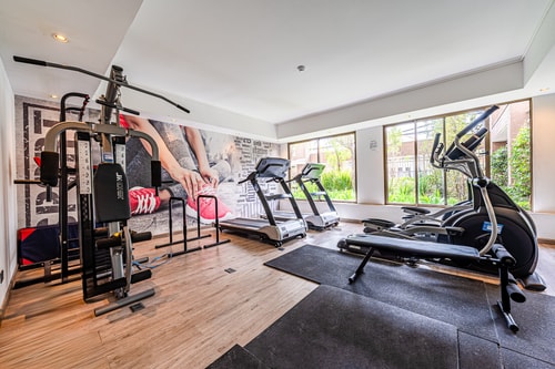 Gimnasio del edificio con máquinas cardiovasculares y ventanales
