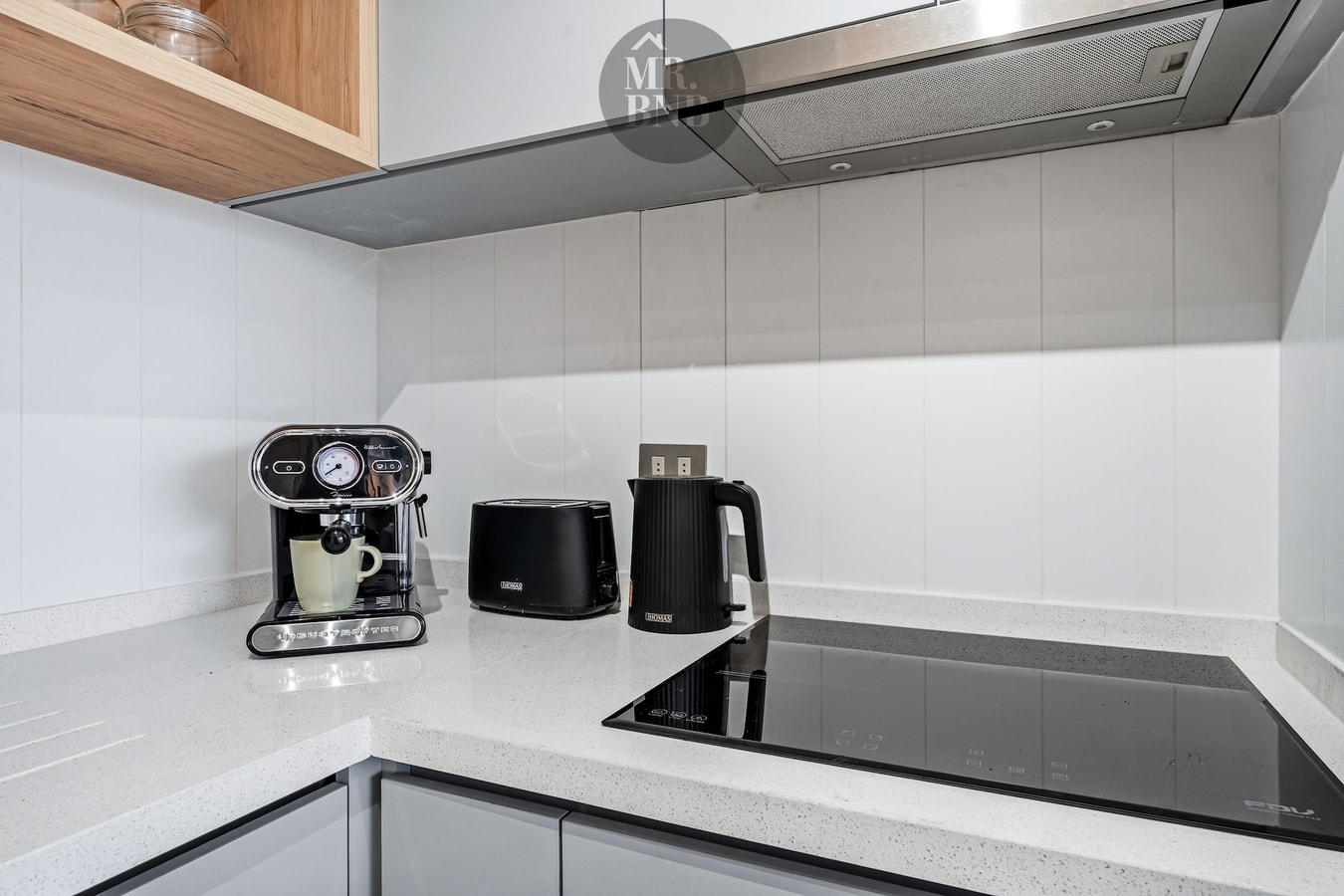 Detalle de encimera de cocina con cafetera espresso, hervidor, tostador y cocina de inducción