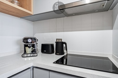 Detalle de encimera de cocina con cafetera espresso, hervidor, tostador y cocina de inducción
