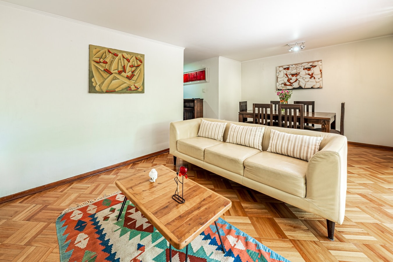 Living con sofá color crema, mesa de centro de madera y alfombra de diseño étnico.