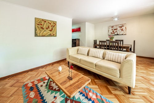 Living con sofá color crema, mesa de centro de madera y alfombra de diseño étnico.