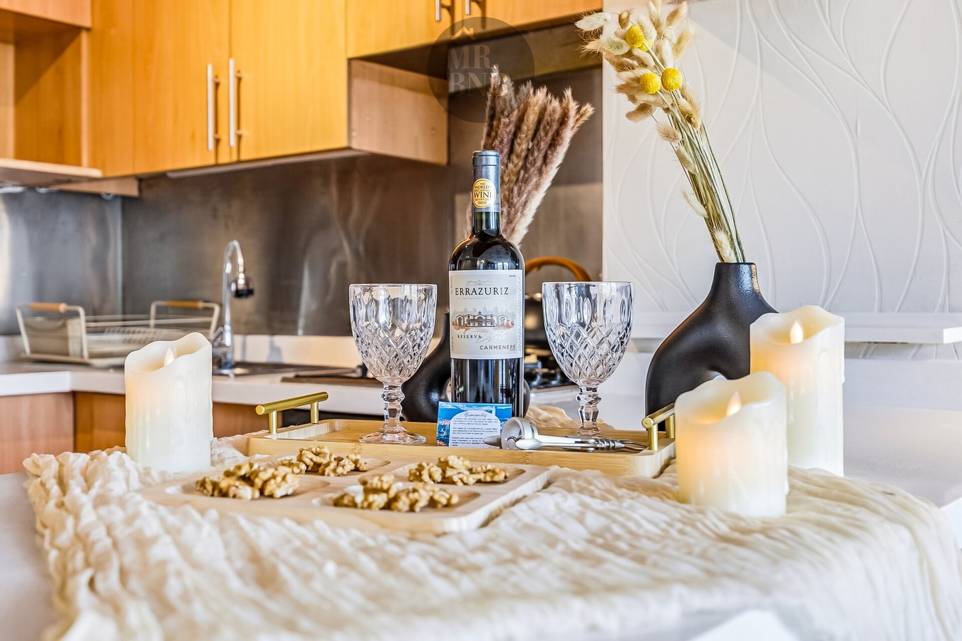 Detalle de mesa con copas, botella de vino y velas decorativas.