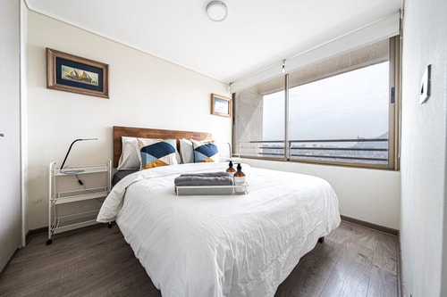 Dormitorio con cama y ventana lateral con vista a la ciudad