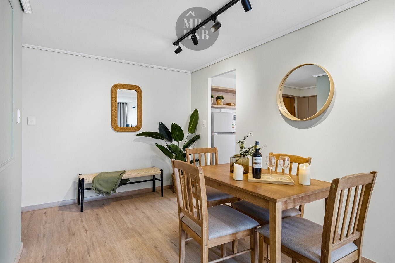 Comedor con mesa de madera, banca, espejo redondo y planta