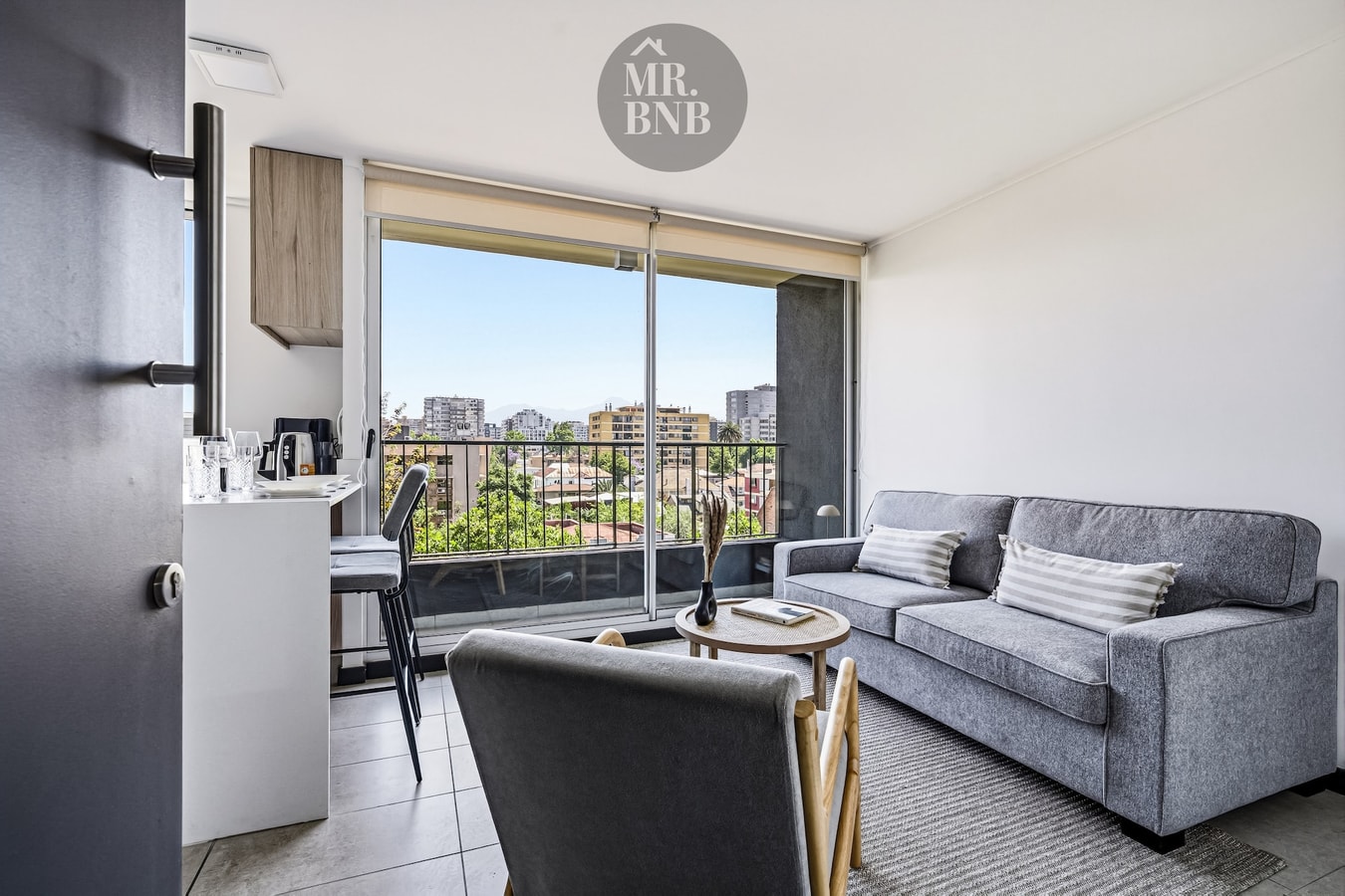 Living con sofás grises, mesa de centro y ventanal con vista a la ciudad