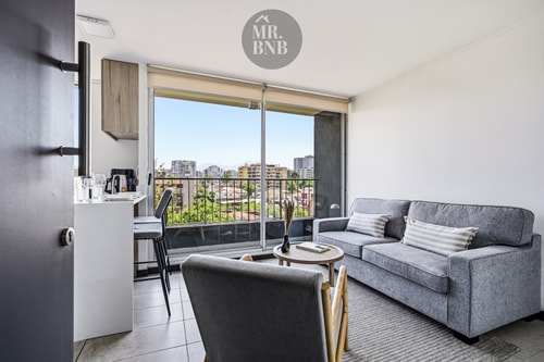 Living con sofás grises, mesa de centro y ventanal con vista a la ciudad