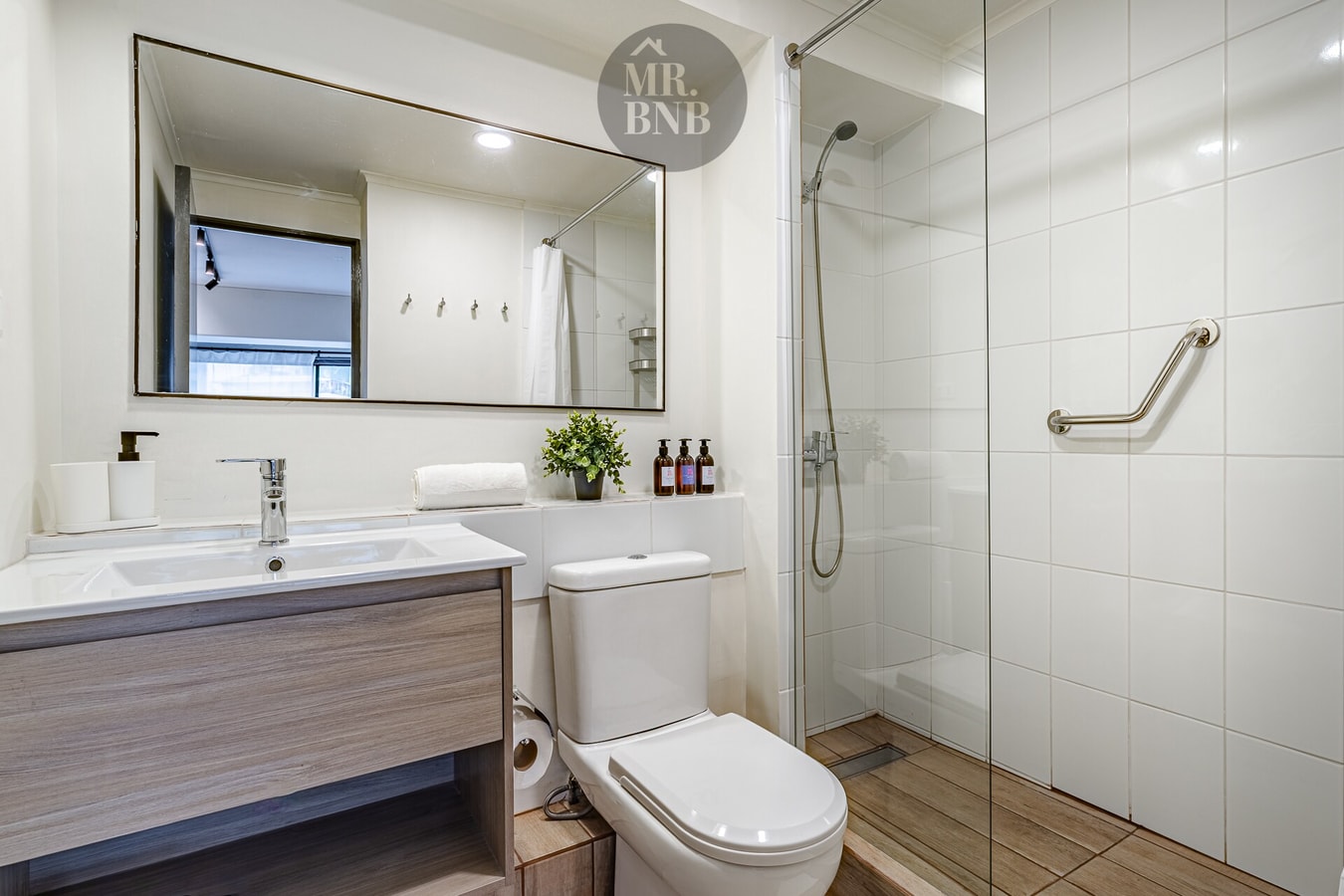 Baño con ducha, lavamanos, inodoro y espejo grande