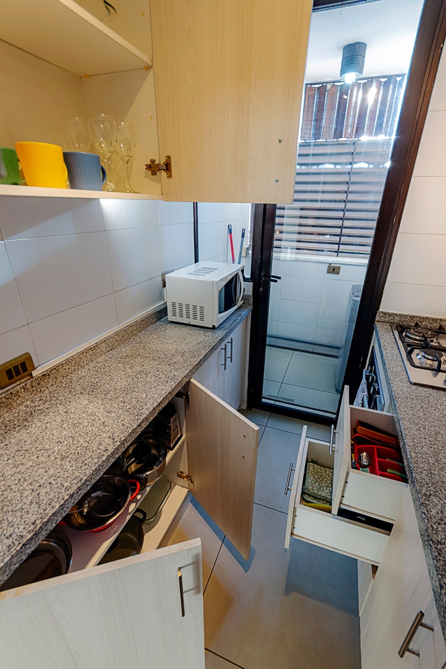 Cocina con muebles y cajones abiertos mostrando ollas y utensilios.