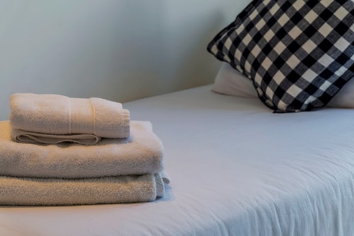 Detalle de toallas dobladas y cojín a cuadros sobre la cama