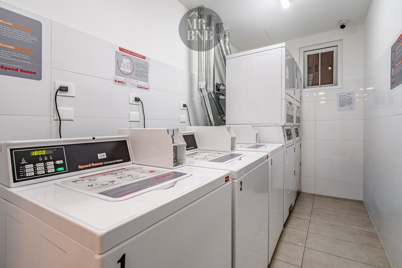 Sala de lavandería del edificio con lavadoras y secadoras industriales