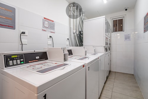 Sala de lavandería del edificio con lavadoras y secadoras industriales