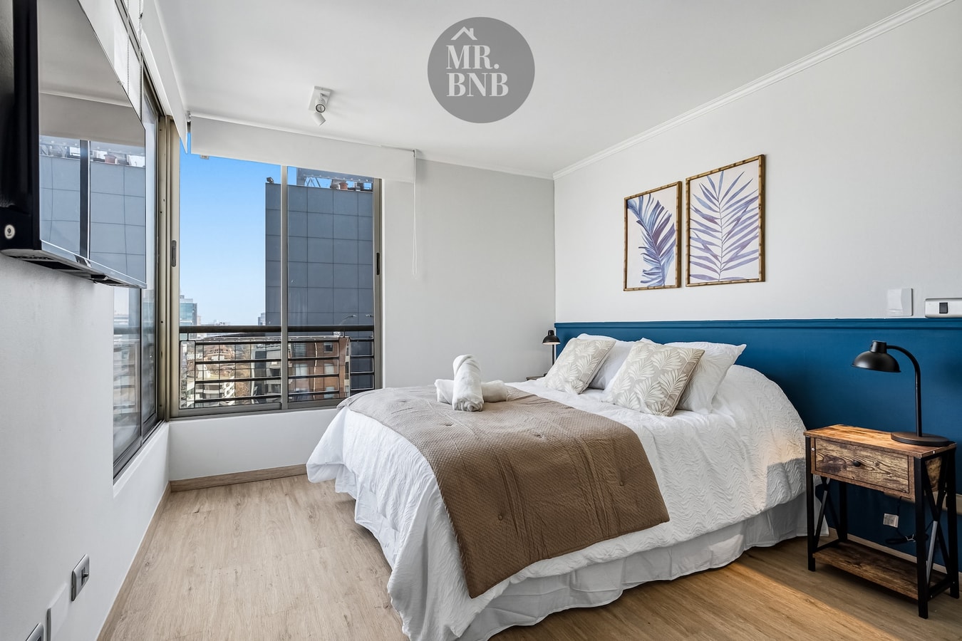 Dormitorio principal con cama de dos plazas, cabecera azul y veladores con lámparas