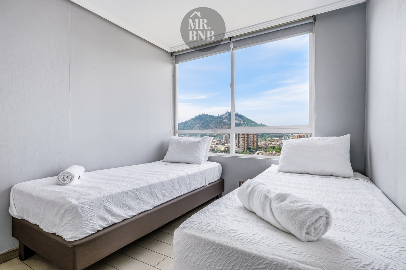 Dormitorio con dos camas individuales, ventanal amplio y vista a la ciudad y cordillera