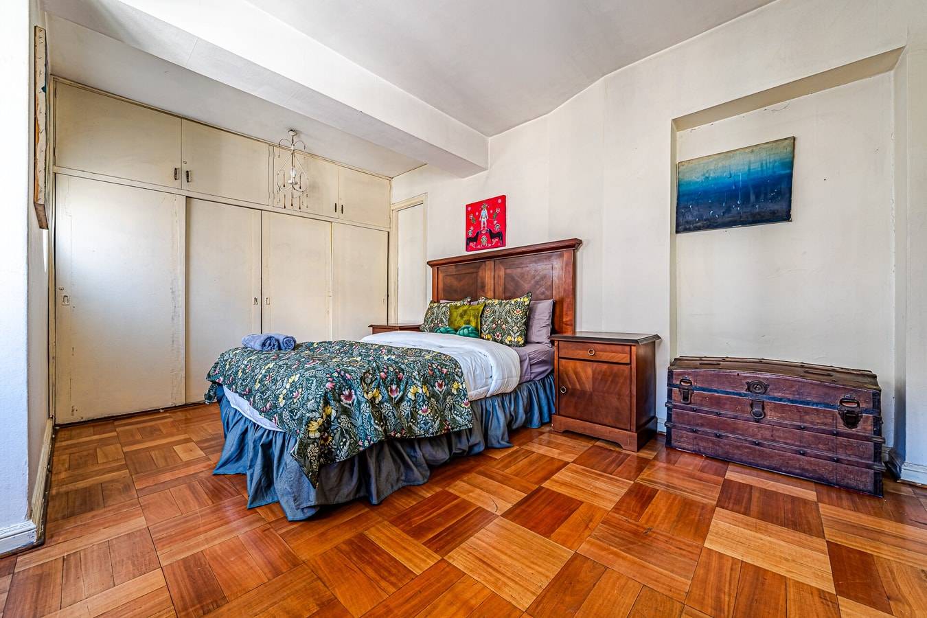 Dormitorio con cama matrimonial, ropero empotrado y baúl de madera
