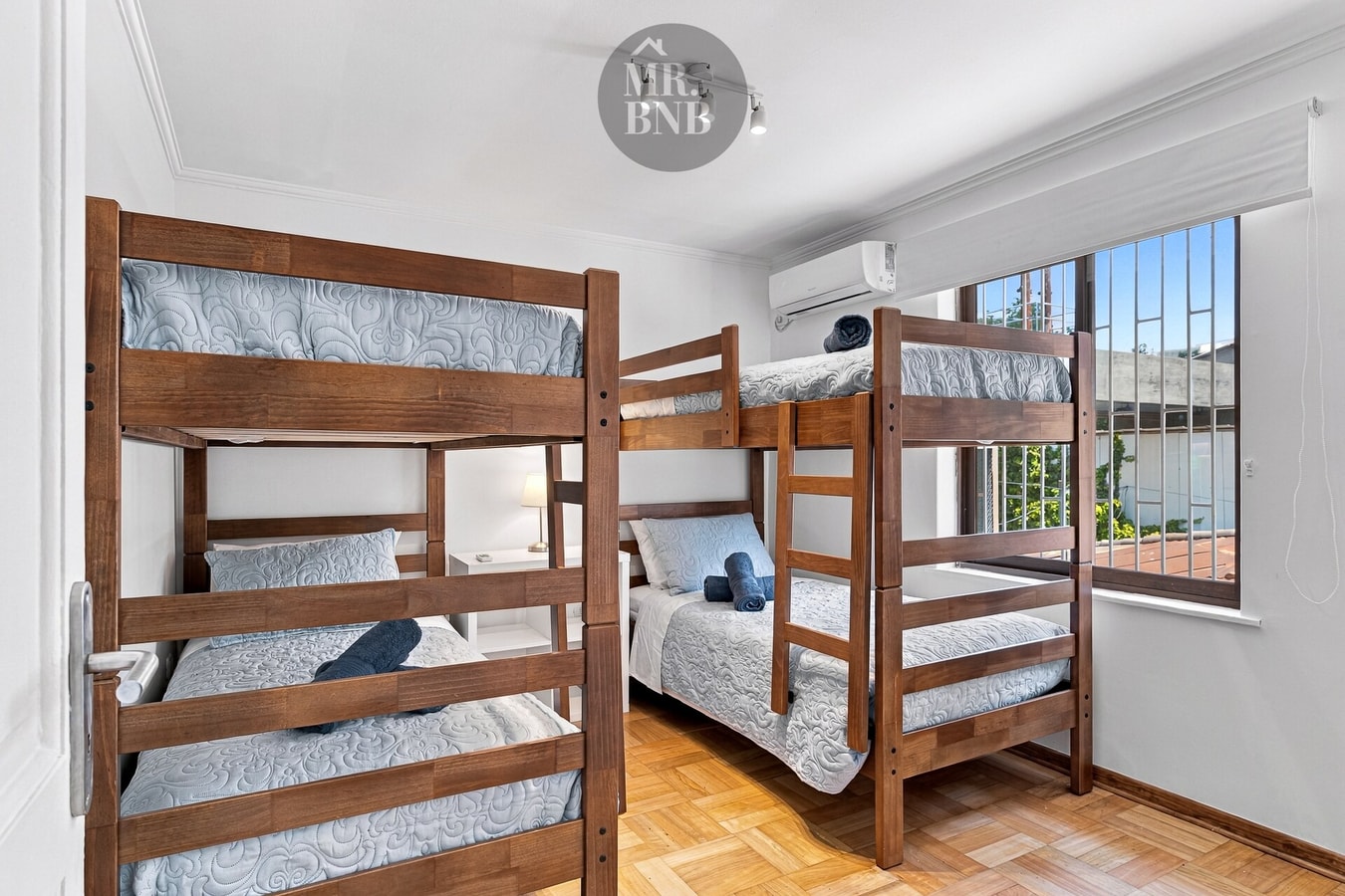 Dormitorio con dos camarotes de madera, cuatro camas en total, y aire acondicionado.