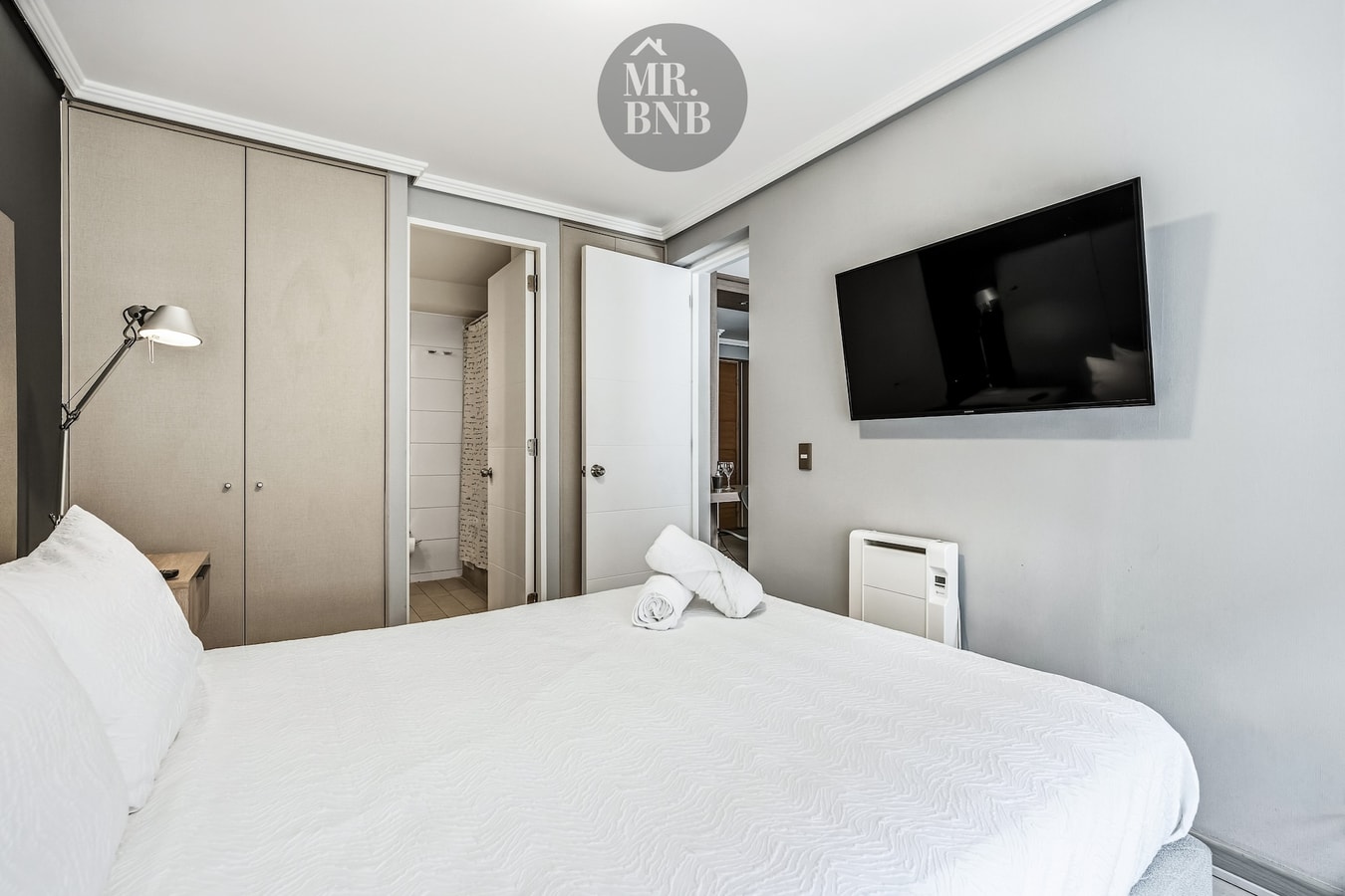Dormitorio con cama, clósets empotrados y televisor en la pared