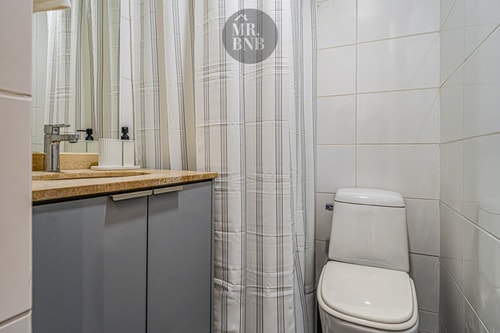 Baño con lavamanos sobre mueble, cortina de baño a rayas e inodoro