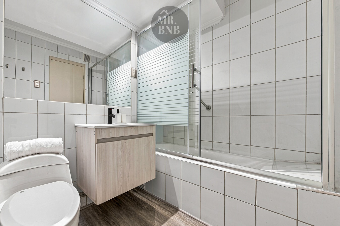 Baño con tina ducha, vanitorio colgante y llaves cromadas.