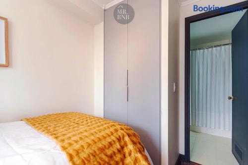 Dormitorio con cama, cubrecama mostaza y closet junto a la puerta del baño.