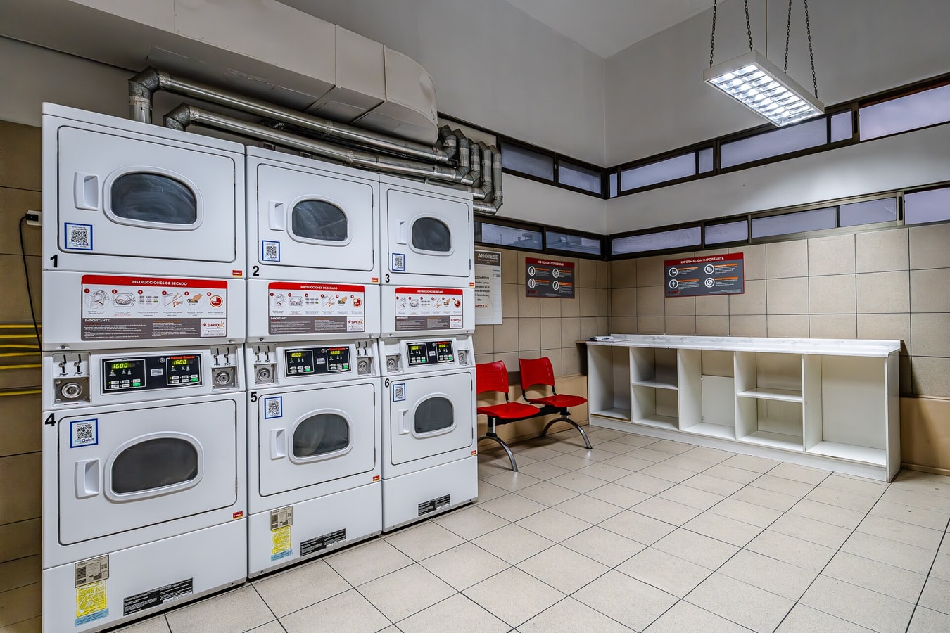 Sala de lavandería del edificio con varias lavadoras y secadoras industriales