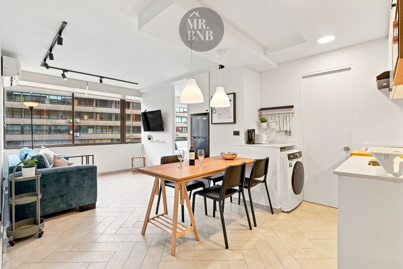 Living comedor con sofá, mesa de madera con sillas y lavadora secadora integrada.