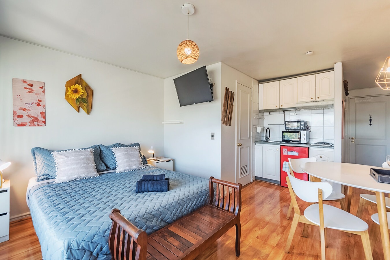Estudio con cama, mesa de comedor, sillas y kitchenette al fondo