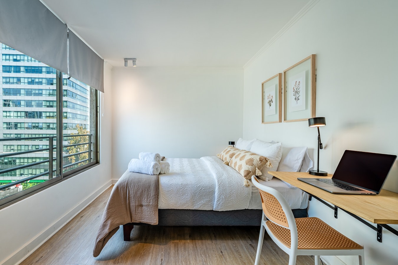 Dormitorio con cama, escritorio y ventana con vista a edificios