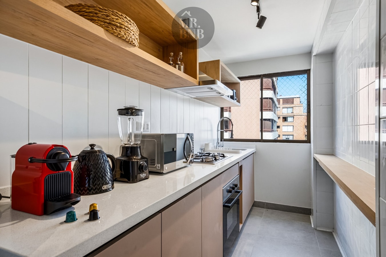 Detalle de cocina con licuadora, microondas y ventana con vista a edificios
