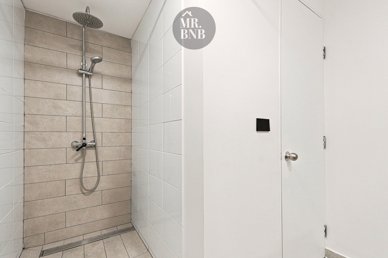 Baño con ducha con revestimiento de madera y puerta de acceso.
