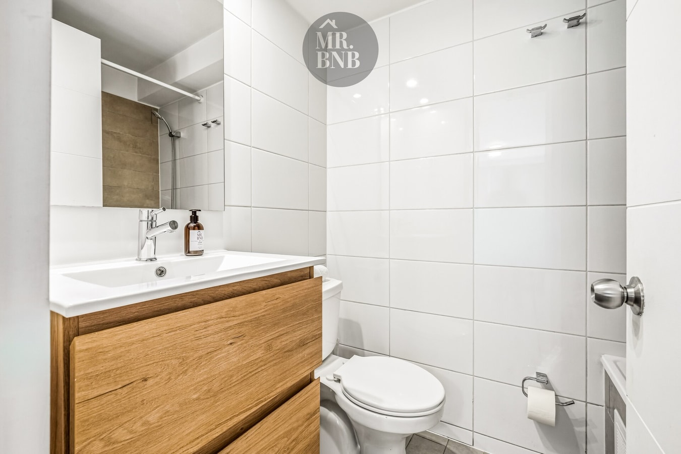 Baño con mueble vanitorio de madera, ducha de vidrio e inodoro