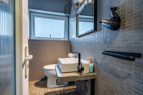 Baño de suite con mosaico gris, lavamanos y secador de pelo