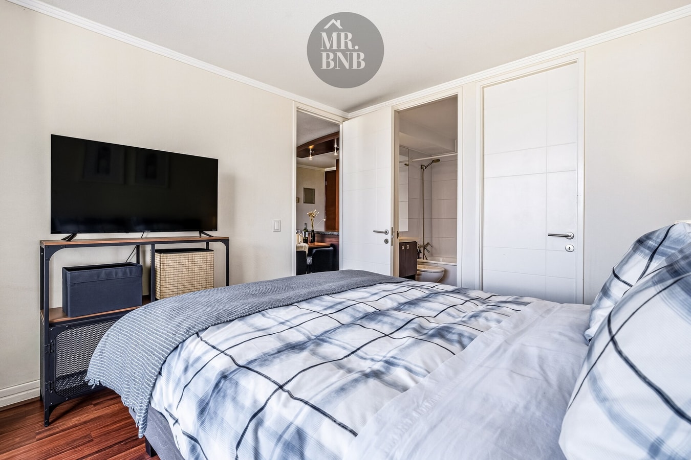 Dormitorio con cama, mueble bajo televisor y puertas de clóset