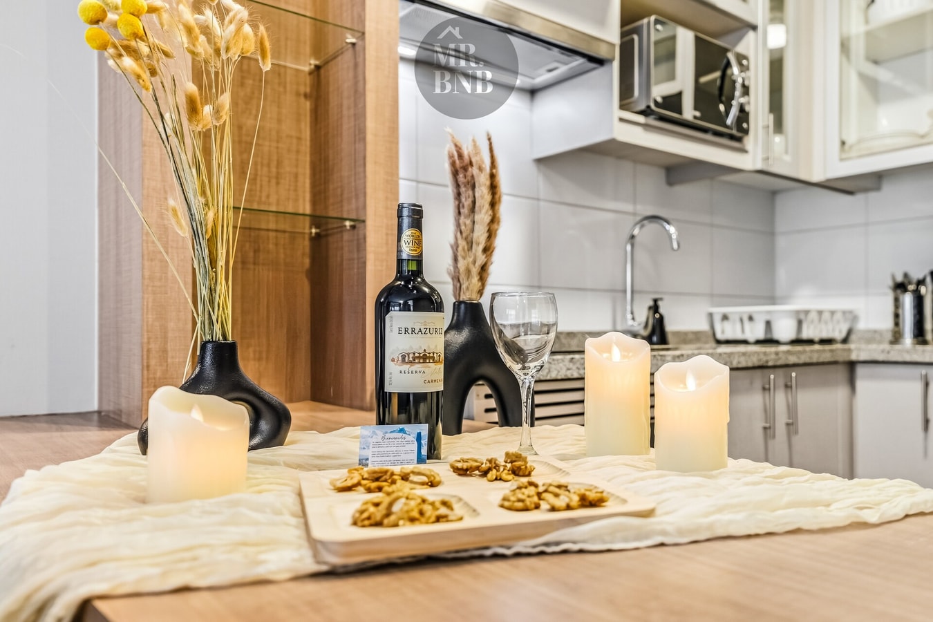 Detalle de mesa con velas, vino, copa y snacks sobre la encimera