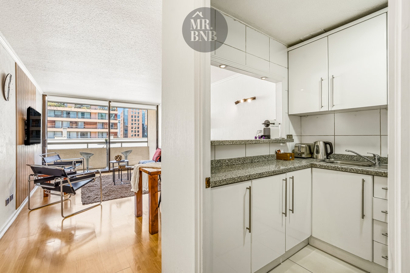 Living comedor integrado a la cocina americana, con ventanal y vista a otros edificios