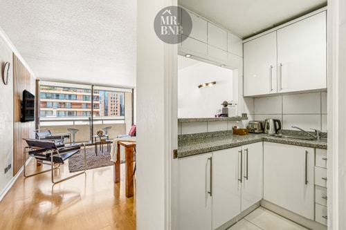 Living comedor integrado a la cocina americana, con ventanal y vista a otros edificios