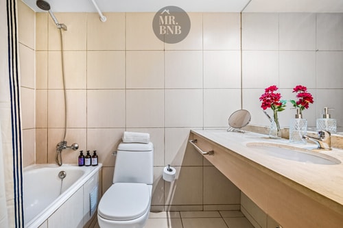 Baño con tina, lavamanos alargado con flores decorativas e inodoro.