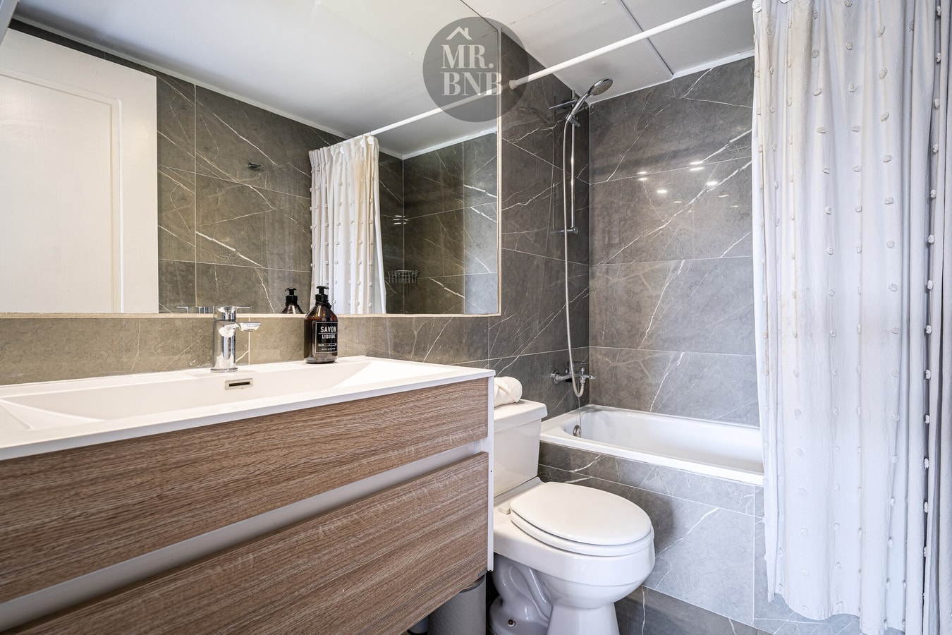 Baño con tina, ducha y mueble vanitorio de madera