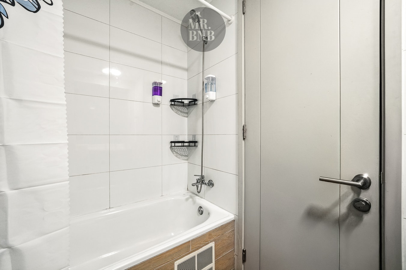 Detalle de tina con ducha y puerta de acceso al baño.